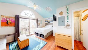 Une chambre à coucher avec un lit, un banc en bois, une télévision et un ventilateur de plafond.