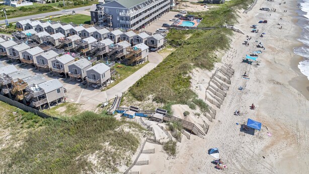 Un hôtel situé sur la côte, doté de plusieurs chambres de style bungalow, d’une plage de sable et d’une promenade qui mène à la plage.