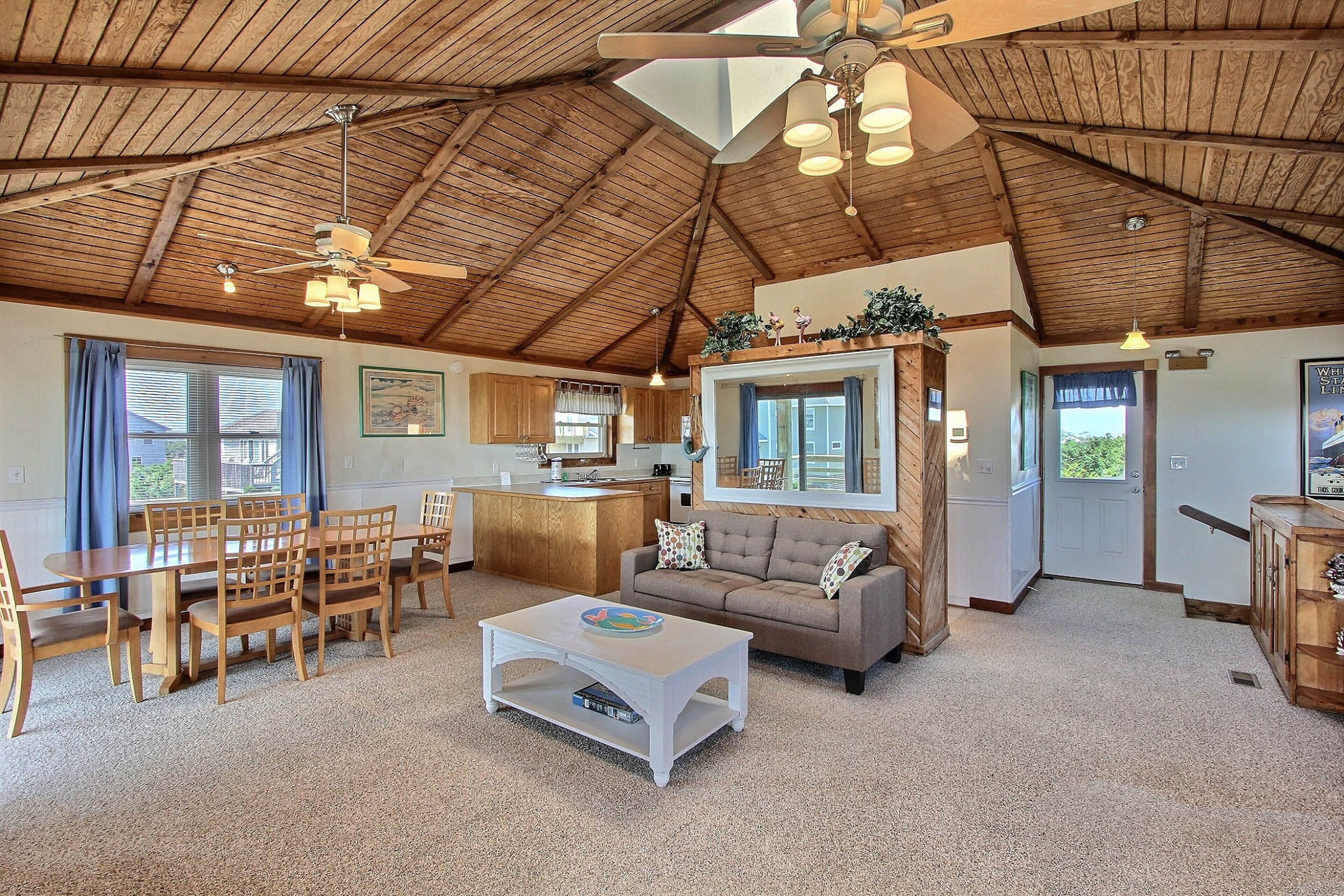 A spacious living area with a high ceiling, wooden furniture, and a central seating arrangement.