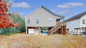 Ein zweistöckiges Haus mit überdachter Veranda und einer Holztreppe, die zum zweiten Stock führt.