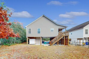 Ein zweistöckiges Haus mit überdachter Veranda und einer Holztreppe, die zum zweiten Stock führt.