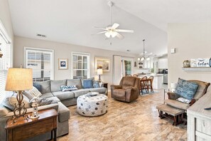 Ein geräumiges Wohnzimmer mit Sofa, Sesseln, einem Couchtisch und einem Essbereich mit Stühlen.