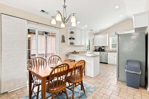 Une cuisine moderne avec un coin repas, comprenant un îlot central, des meubles blancs et un lave-vaisselle encastré.