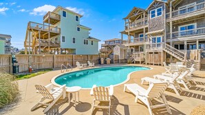 A swimming pool with lounge chairs and wooden deck structures. - Sprawling & luxe home with pool, hot tub, balconies, grill, game room, & AC (Hatteras)