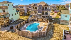 A residential area with multiple two-story houses, a swimming pool, and outdoor seating. - Sprawling & luxe home with pool, hot tub, balconies, grill, game room, & AC (Hatteras)