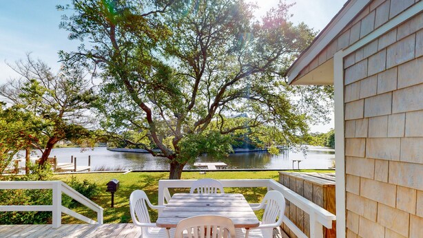 A wooden deck with a table and chairs overlooking a lake. - Waterfront House w/ Water View, Shared Pool, Private Washer/Dryer, & Free WiFi (Frisco)