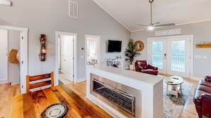 A spacious living area with a fireplace, a ceiling fan, and a sign reading "Oak Island".