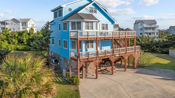 Une maison à deux étages avec un balcon, entourée de verdure.