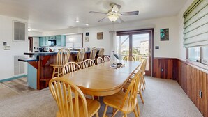 Une cuisine spacieuse avec un coin repas, des armoires en bois et un ventilateur de plafond.