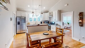 Une cuisine moderne avec des meubles blancs, un îlot central et des luminaires suspendus.