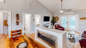 Un vaste espace de vie doté d’une cheminée, d’un ventilateur de plafond et d’une enseigne indiquant « Oak Island ».