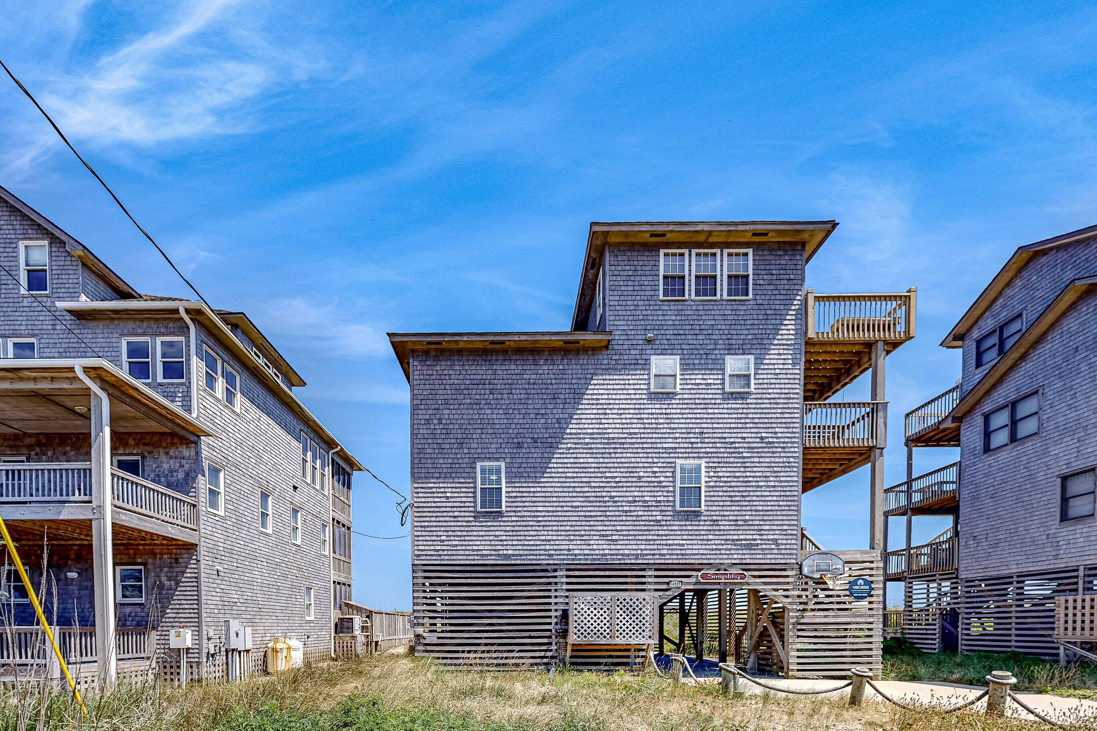 A two-story building with a balcony on the second floor, a wooden fence in front, and a clear blue sky.