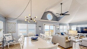 A spacious living area with a dining table, white chairs, a sofa, and a ceiling fan. - Oceanfront dog-friendly home with private hot tub, ocean-view sundecks, AC & W/D (Frisco)