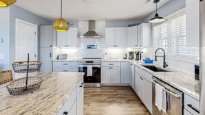 A modern kitchen with white cabinets, a stainless steel oven, and a granite countertop. - Oceanfront dog-friendly home with private hot tub, ocean-view sundecks, AC & W/D (Frisco)