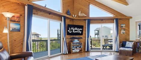 Een ruime zithoek met een groot raam, een open haard en een bord van Hatteras Realty.