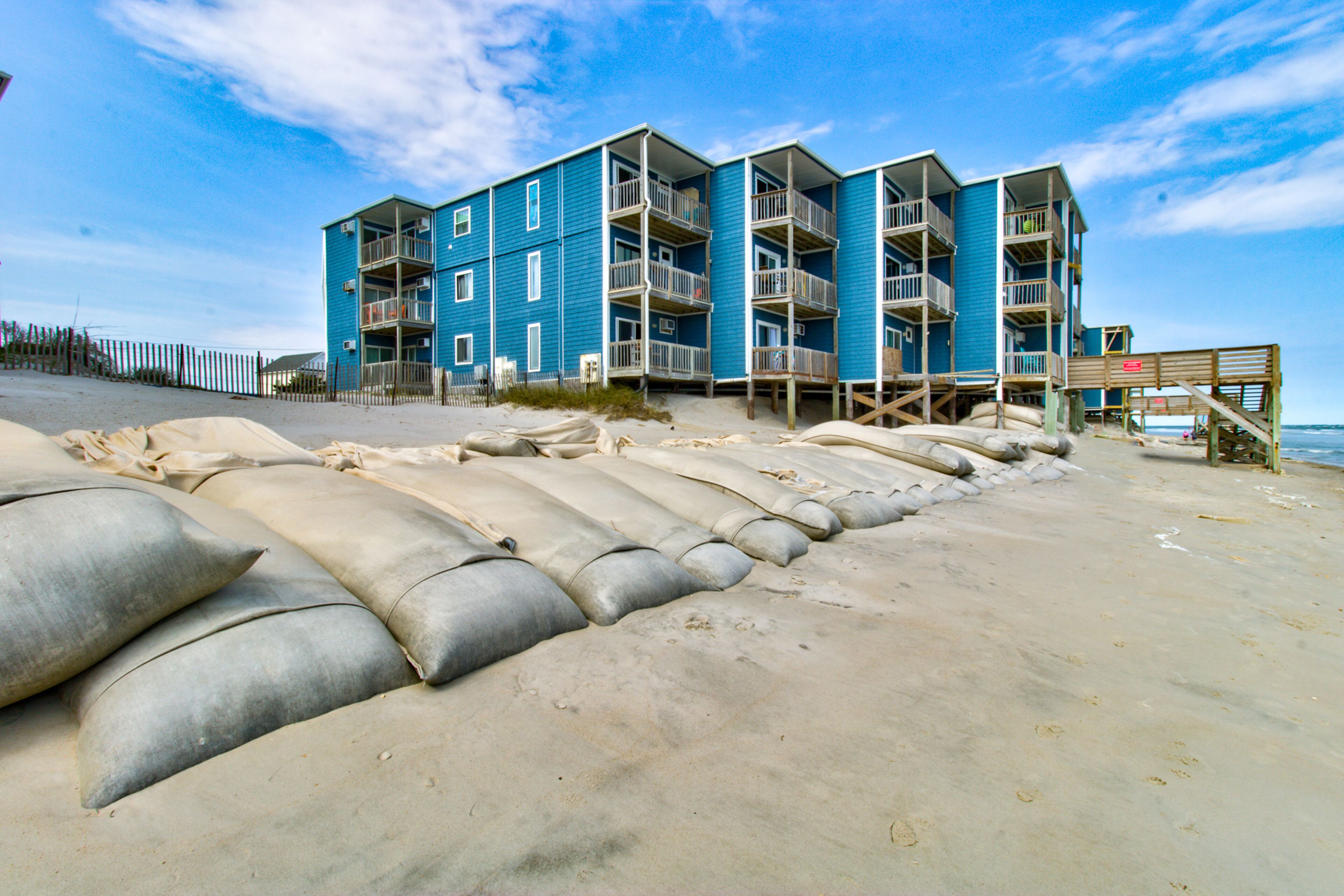 Un edificio de varios pisos con balcones, situado en una playa arenosa.