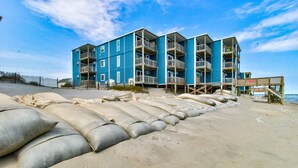 Un edificio de varios pisos con balcones, situado en una playa arenosa.