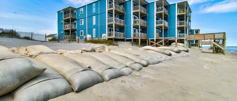 A multi-story building with balconies, located on a sandy beach.