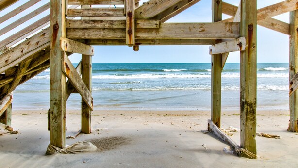 Una estructura de madera en la playa con vista al océano.