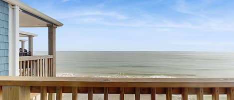 A wooden deck overlooking a beach with a building in the background.