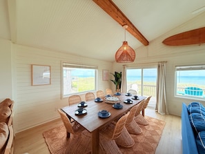 A dining area with a wooden table, wicker chairs, and a hanging light fixture.