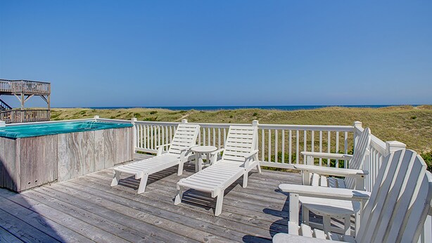 A wooden deck with white lounge chairs and a small pool, overlooking a beach. - Luxury beach home with beach view, private hot tub, & fireplace (Avon)