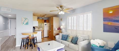 A spacious living area with a dining table, a sofa, and a ceiling fan.