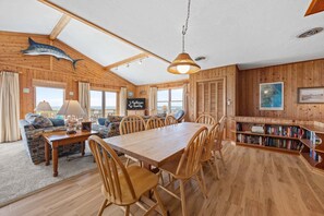 Un intérieur en bois comprenant une table à manger, des chaises, un canapé, une bibliothèque et un grand poisson décoratif accroché au mur.