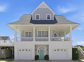 Ein zweistöckiges Haus mit Balkon, Veranda und zwei Garagentoren.