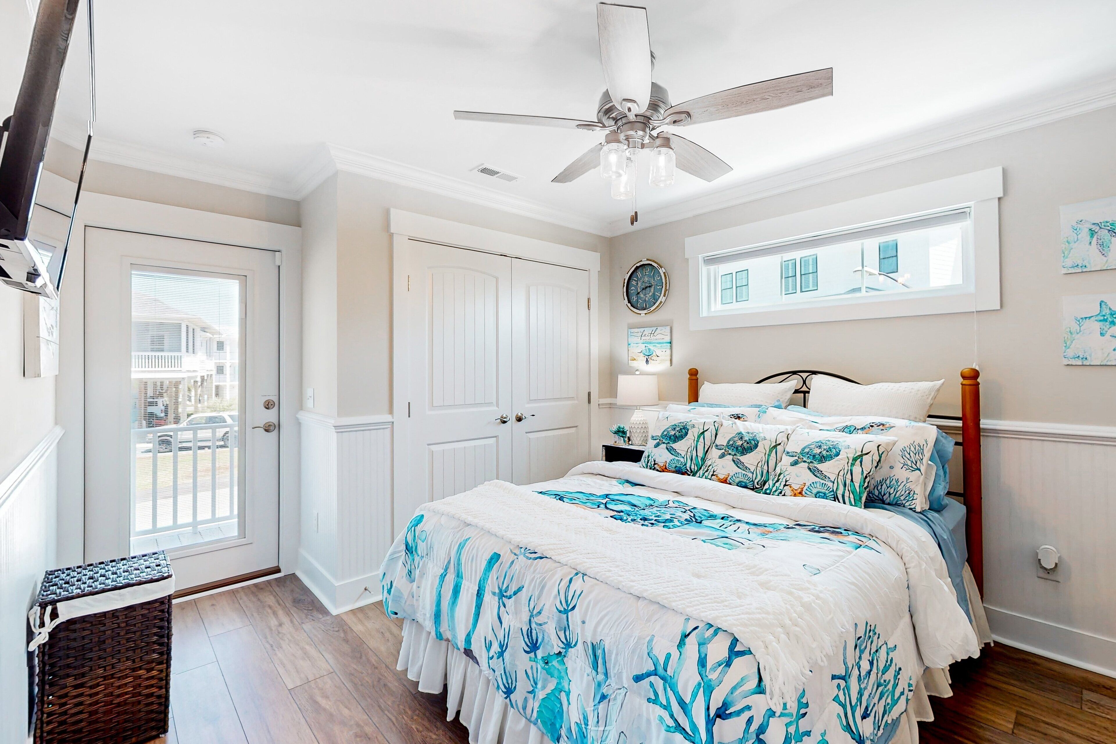 A bedroom with a bed, a ceiling fan, a window, and a door.