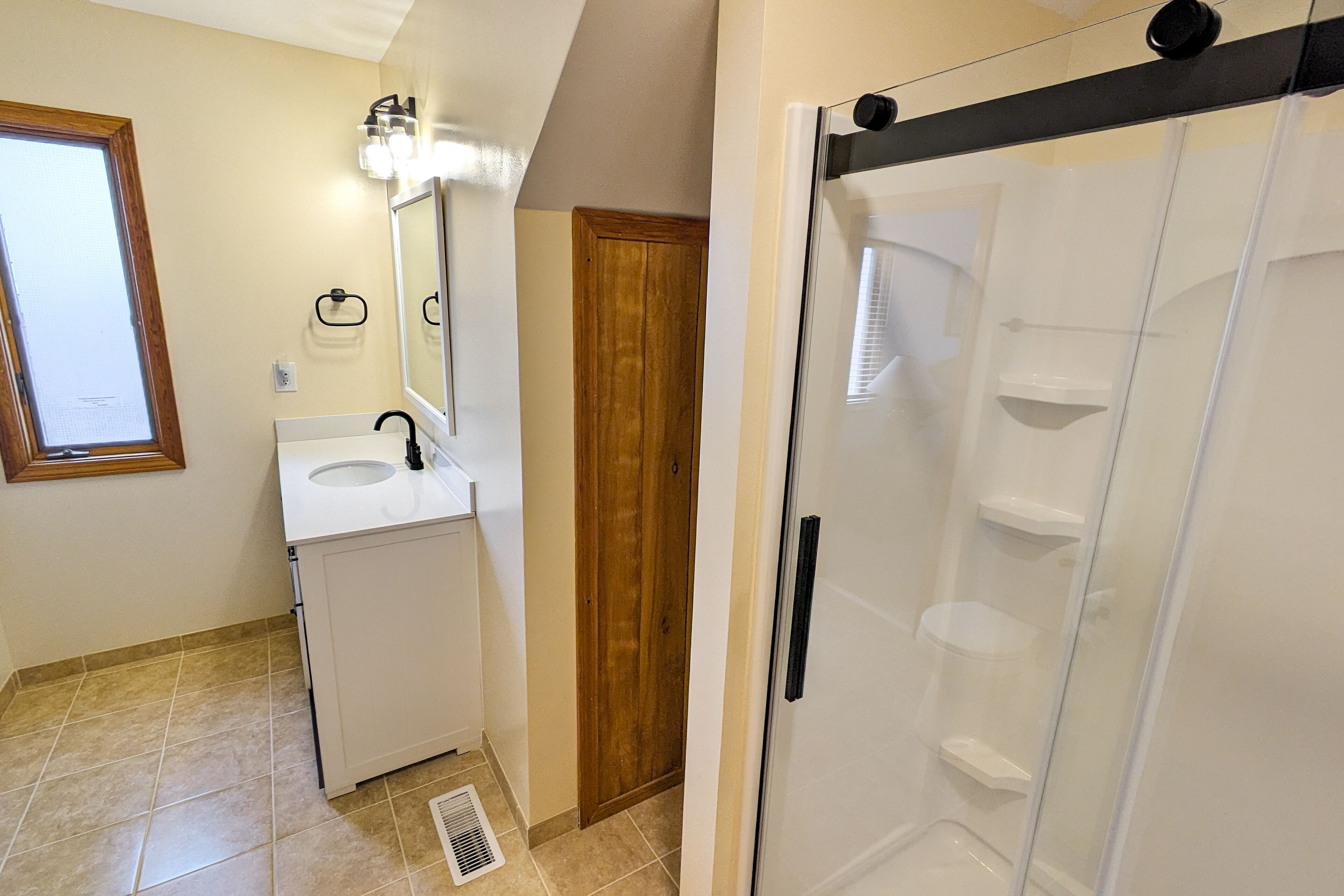 A bathroom with a sink, mirror, and shower.