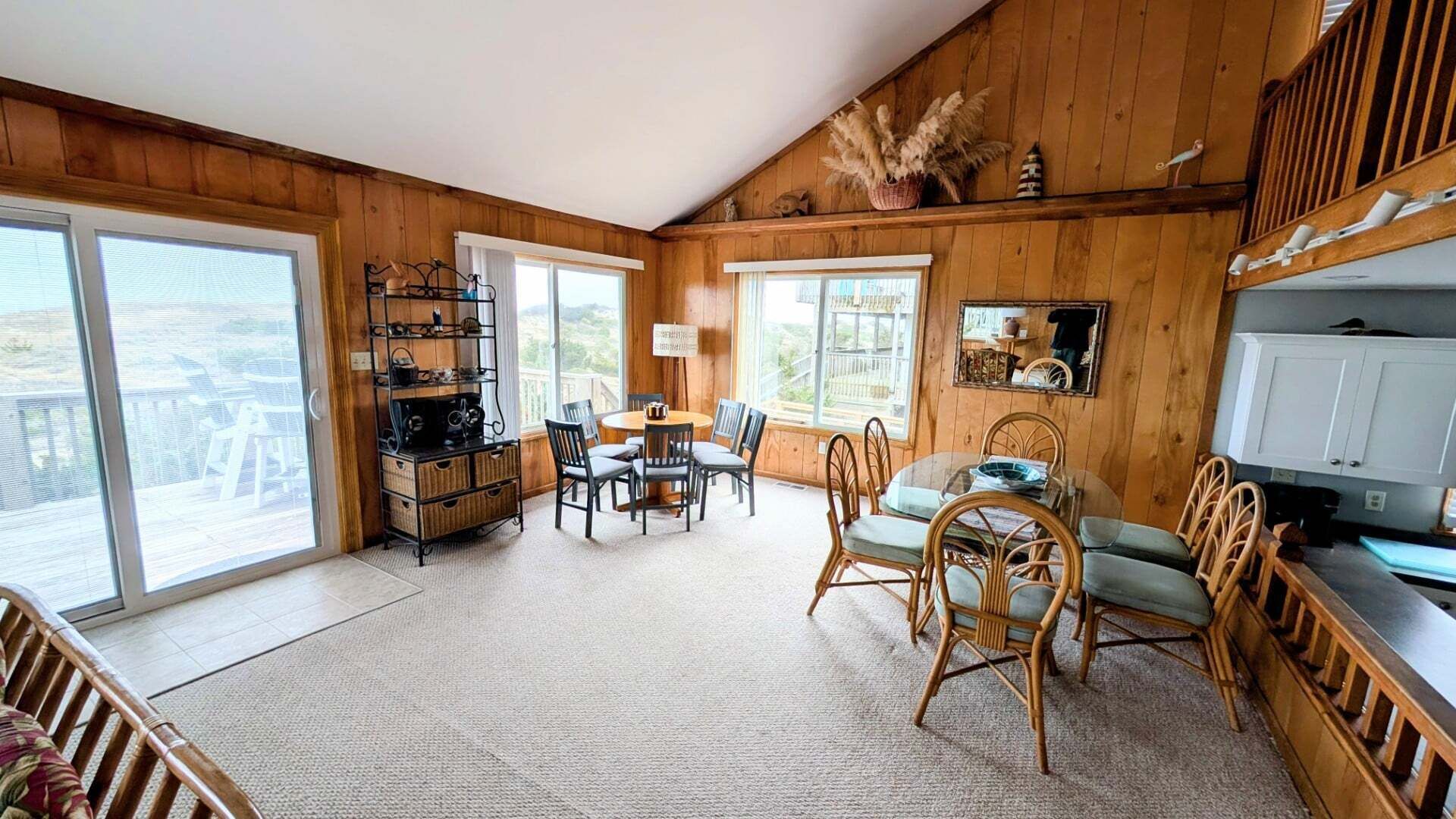 A cozy room with a wooden interior, a dining area with chairs and a table, and a large window offering a view.