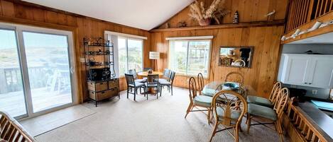 A cozy room with a wooden interior, a dining area with chairs and a table, and a large window offering a view.