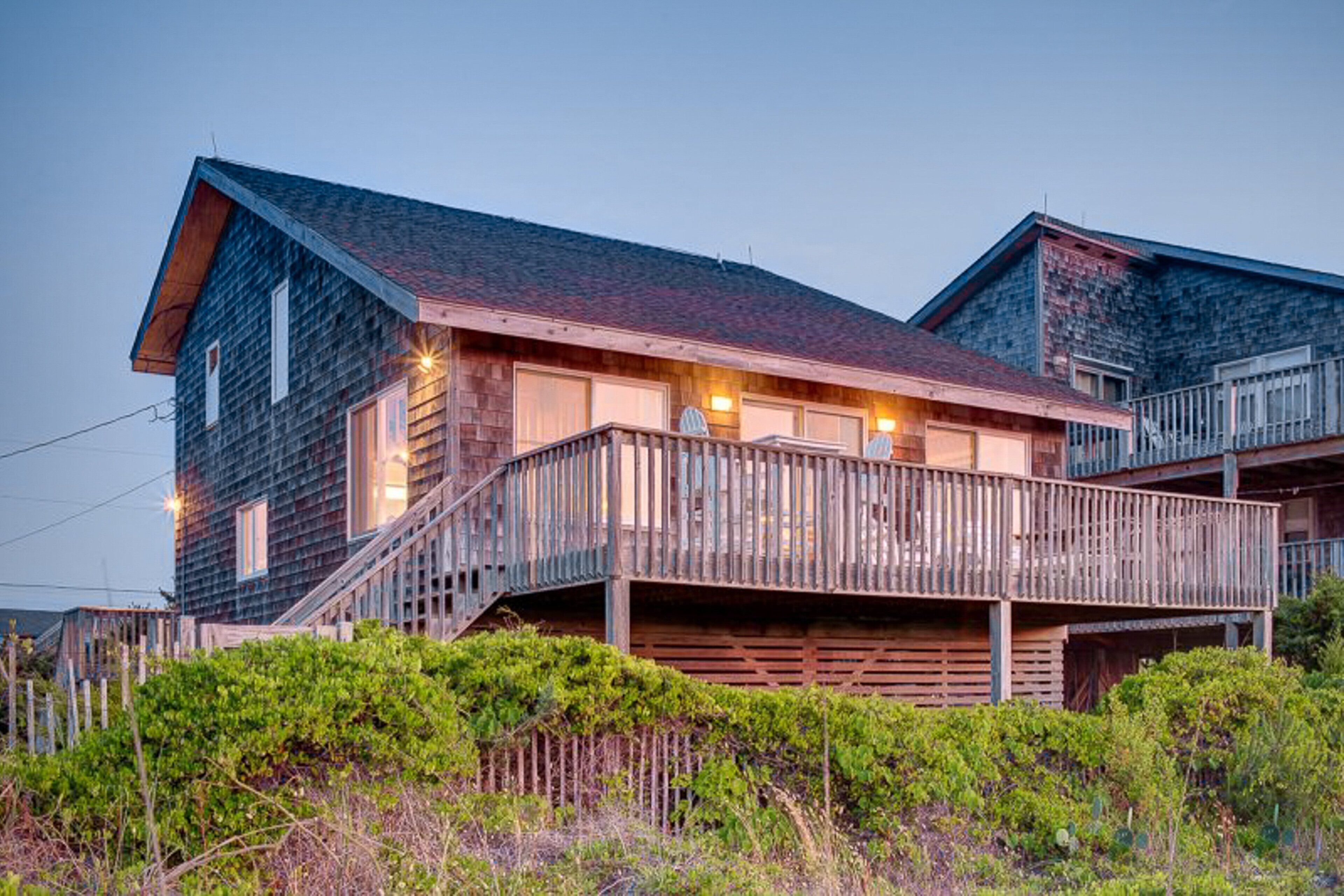 A wooden cabin with a balcony, a staircase, and a porch.