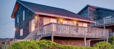 A wooden cabin with a balcony, a staircase, and a porch.