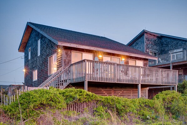 A wooden cabin with a balcony, a staircase, and a porch.