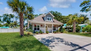 A two-story house with a front porch, a garage, and a well-maintained lawn. - Knee Deep: Family friendly, near beach (Oak Island)