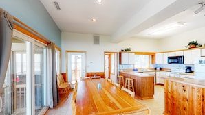 A spacious kitchen with wooden cabinets, a central island, and a large dining table. - Waterfront House w/ Sound View, Shared Pool, Private W/D, Private Hot Tub (Frisco)