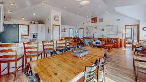 Ett rymligt vardagsrum med ett stort matbord i trä, omgivet av stolar, en soffa och ett soffbord.