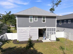 A two-story residential building with a covered patio area and a fenced backyard.