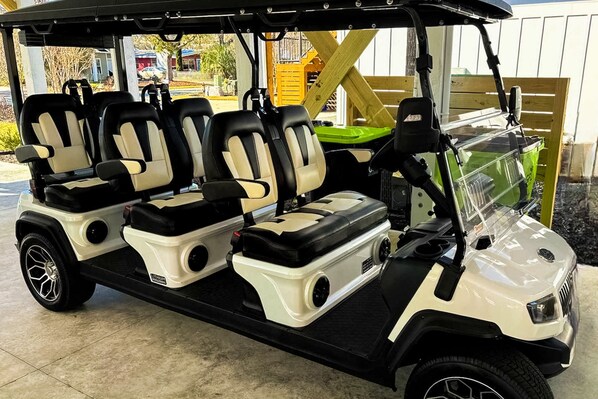 A golf cart with three seats, a storage compartment, and a windshield.
