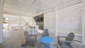A covered patio area with a table and chairs, a bench, and a view of the outdoors. - Anchor Forty-Five: Coastal home with large deck, close to beach and local attractions (Oak Island)