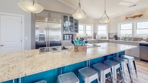 A modern kitchen with a large island, stainless steel appliances, and a view of the city. - Live Like Royalty in This 9-Bedroom Oceanfront Retreat (North Topsail Beach)