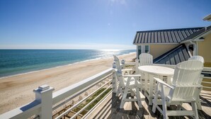 A deck with a view of the beach, white chairs, and a table. - Live Like Royalty in This 9-Bedroom Oceanfront Retreat (North Topsail Beach)