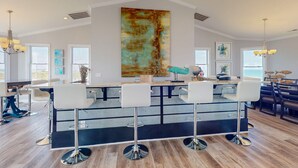 A modern kitchen with a central island, bar stools, and large windows. - Live Like Royalty in This 9-Bedroom Oceanfront Retreat (North Topsail Beach)
