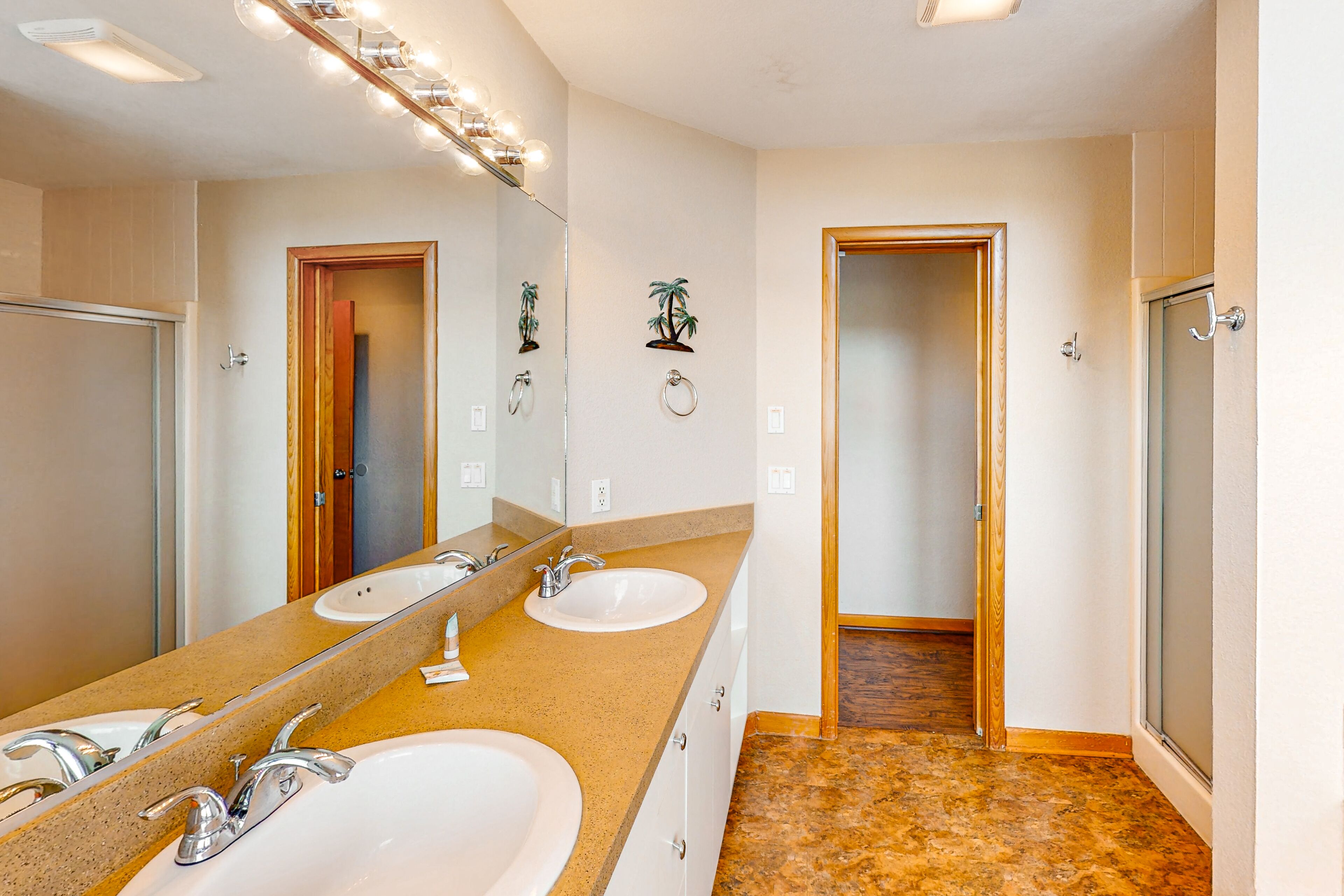 A bathroom with two sinks, a large mirror, and a shower area.