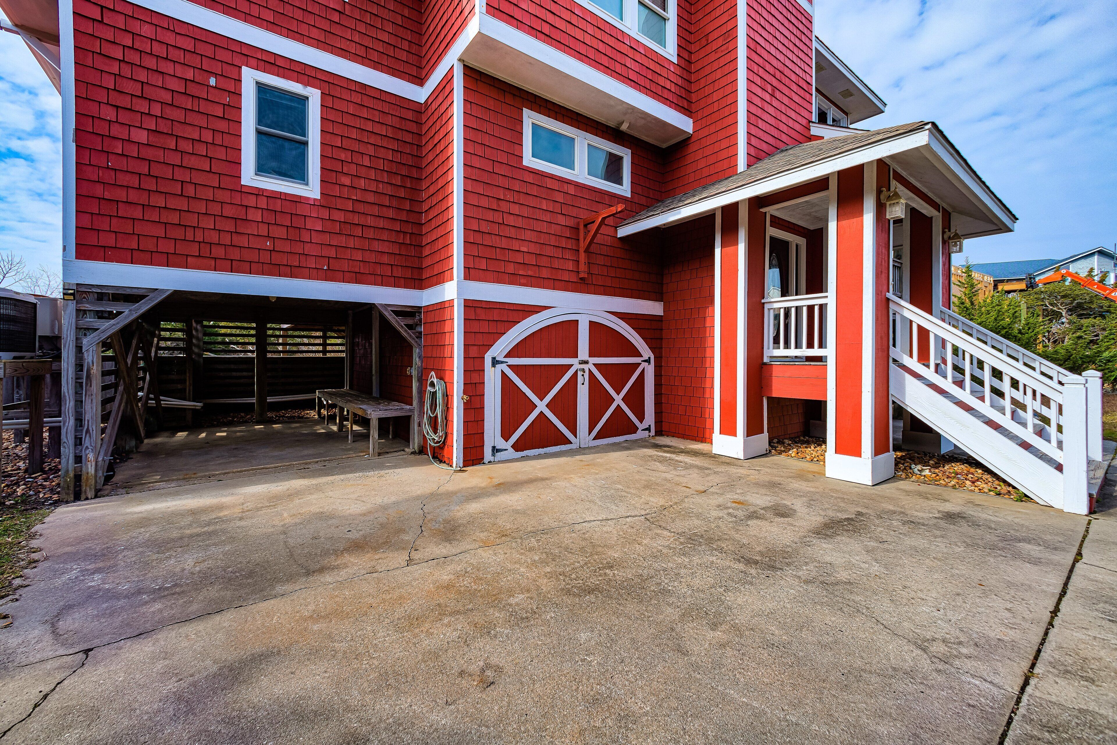 A red building with a garage, a covered porch, and a staircase leading to the entrance.