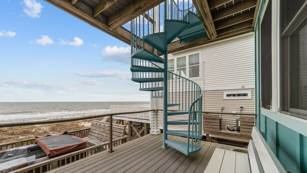 A spiral staircase leading to a balcony overlooking the ocean. - Wave Watcher: Stunning ocean front home with private hot tub and direct beach access (Oak Island)