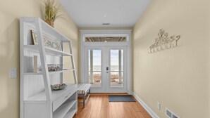 A hallway with a white console table, a bench, and a decorative wall piece. - Wave Watcher: Stunning ocean front home with private hot tub and direct beach access (Oak Island)