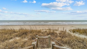 A wooden boardwalk leading to a beach with a clear sky and ocean view. - Wave Watcher: Stunning ocean front home with private hot tub and direct beach access (Oak Island)